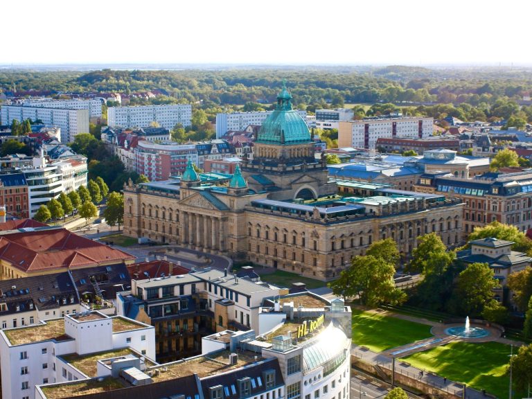 Detektei Leipzig | Wirtschaftsermittlungen Blick auf ein historisches Gebäude mit Kupferkuppel und umliegender Stadtlandschaft. Bundesverwaltungsgericht Leipzig